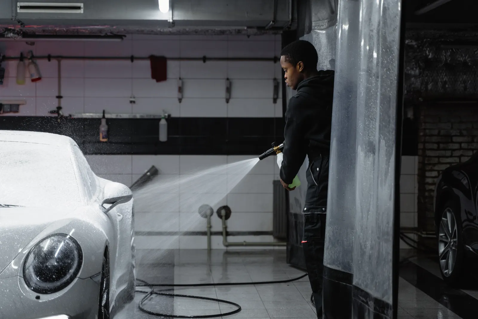 A white daily driver being washed in a detailing bay