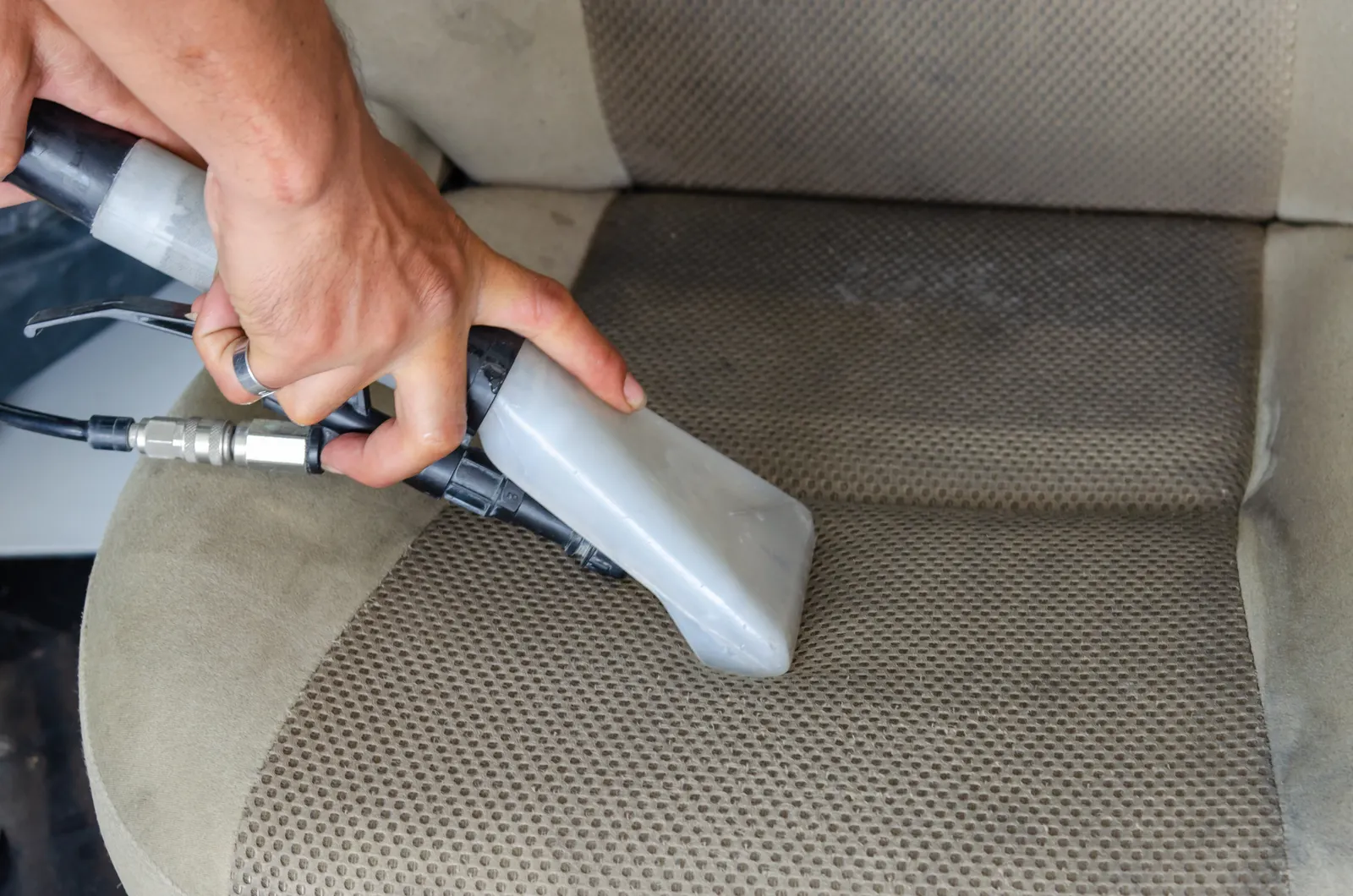 An extraction nozzle cleaning the fabric of a car seat