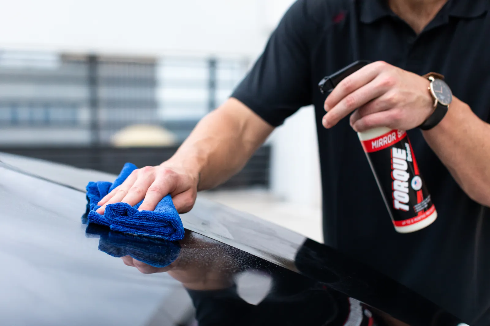 A microfiber cloth and spray used to wipe a vehicle exterior