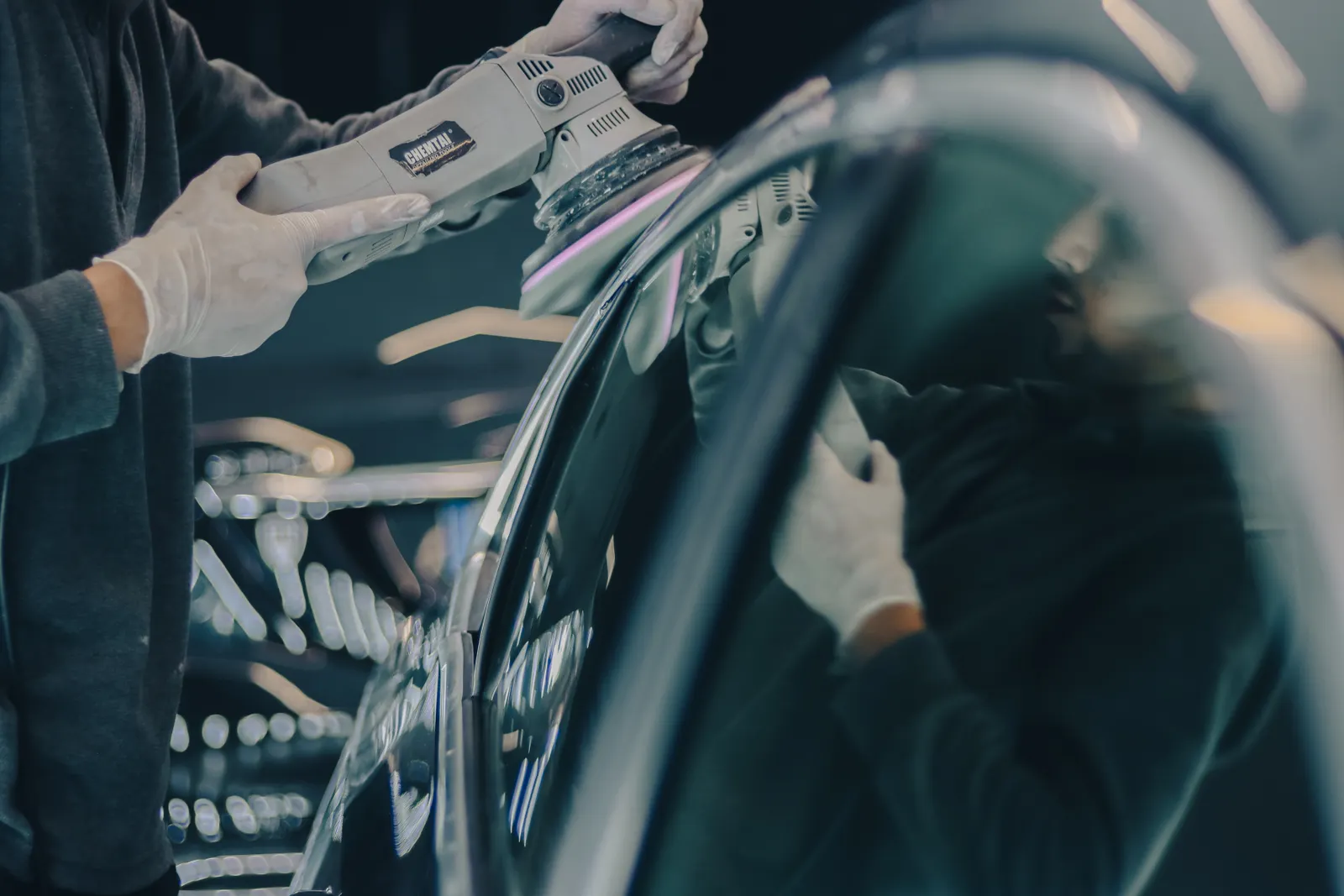 A machine polisher refining a reflective vehicle panel