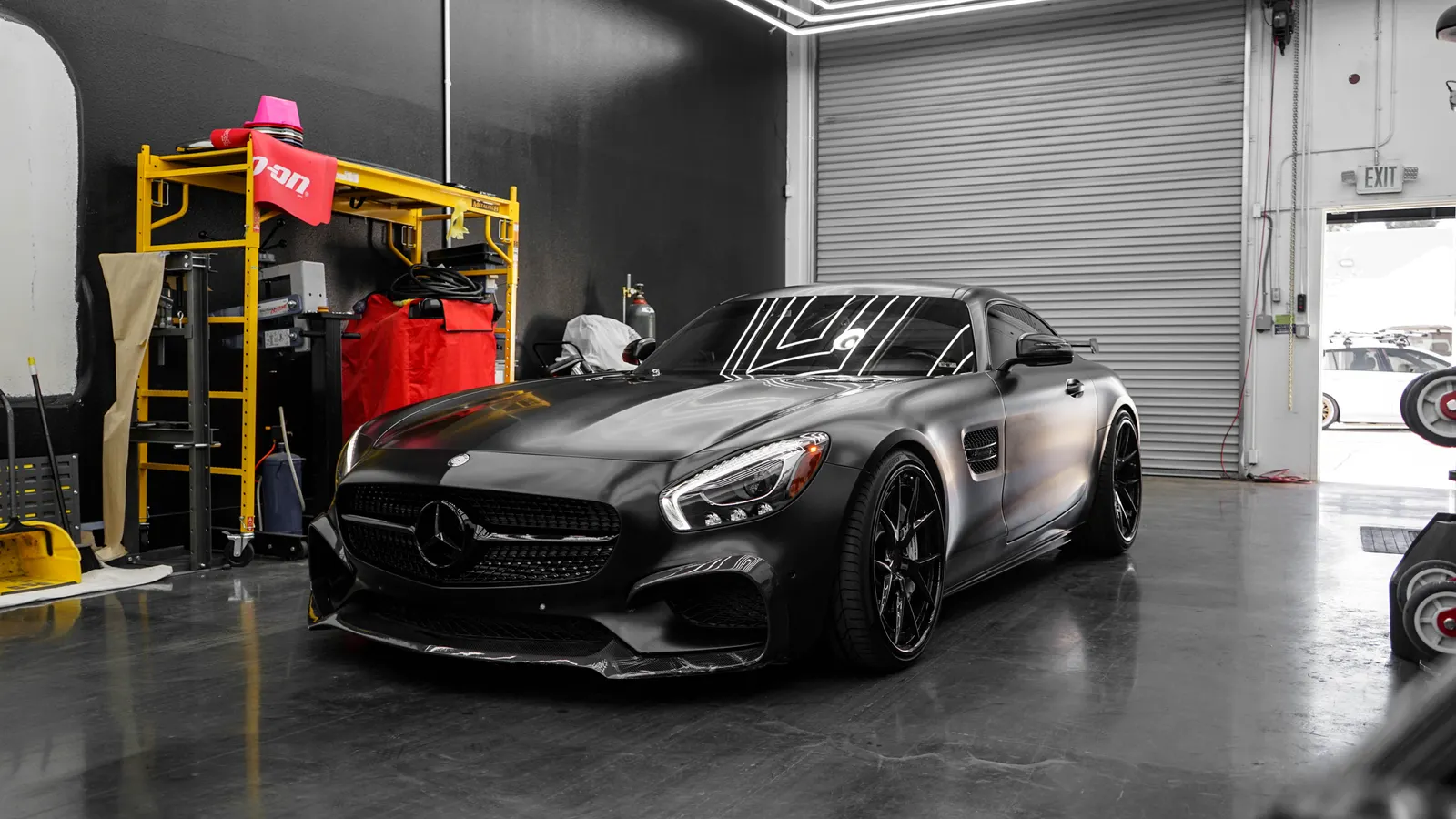 A black coupe with reflective bodywork parked in a garage